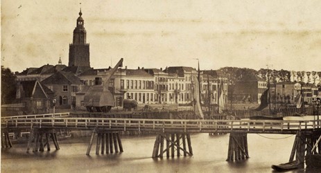<p>Deze foto toont de situatie aan de IJsselkade in 1863 met de oude stadskraan en de in 1858 aangelegde noodbrug. Het deel van de kade ten zuiden van de Marspoortstraat is inmiddels voorzien van nieuwe bebouwing. Het huis op de zuidelijke hoek van de Marspoortstraat (tegenover IJsselkade 12 - Marspoortstraat 1) is al voltooid, terwijl aan de noordzijde nog oudere bebouwing staat (RAZ). </p>
